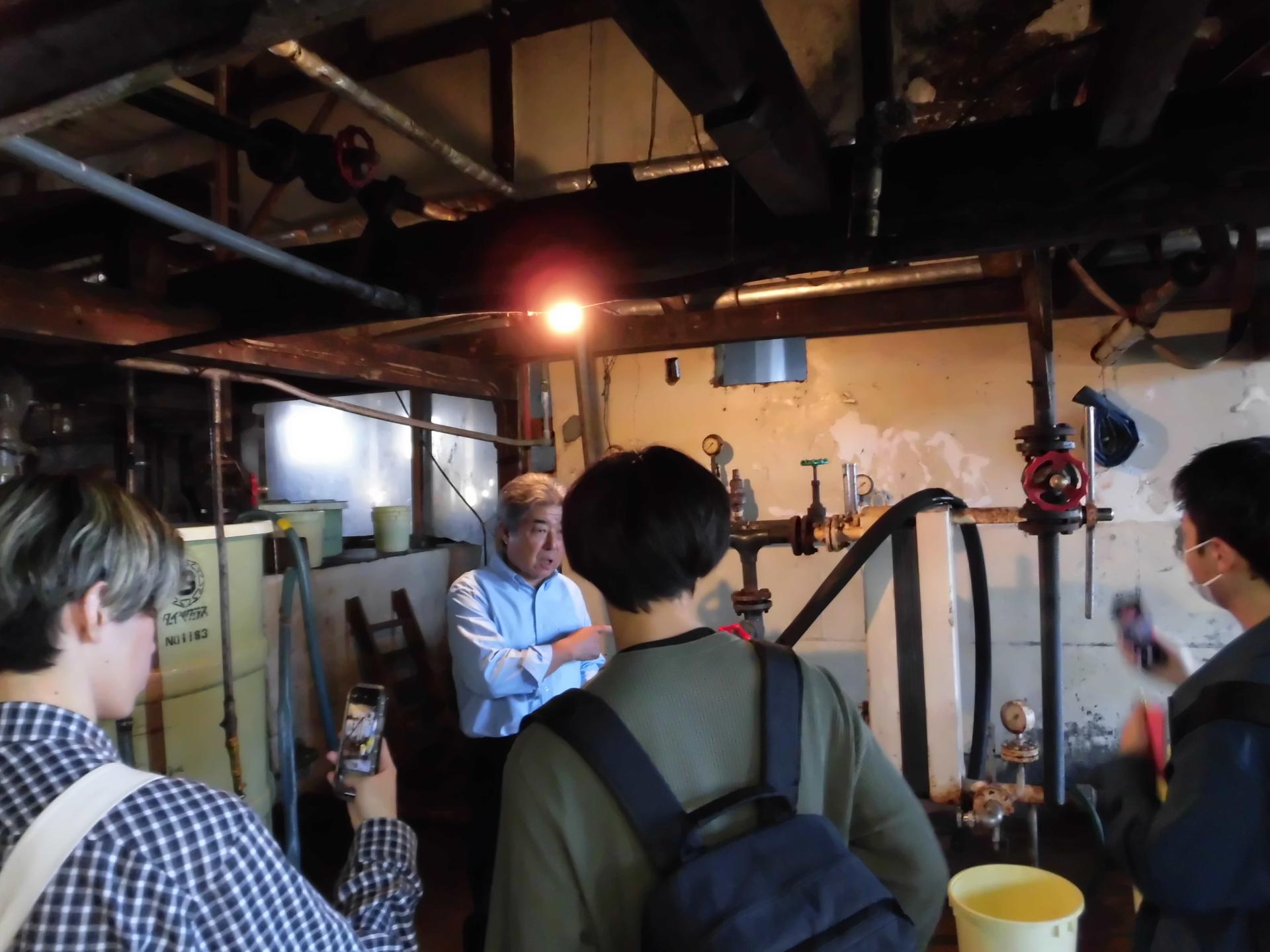 担当者から伊富味噌醤油店の工場内の説明を受ける大学生