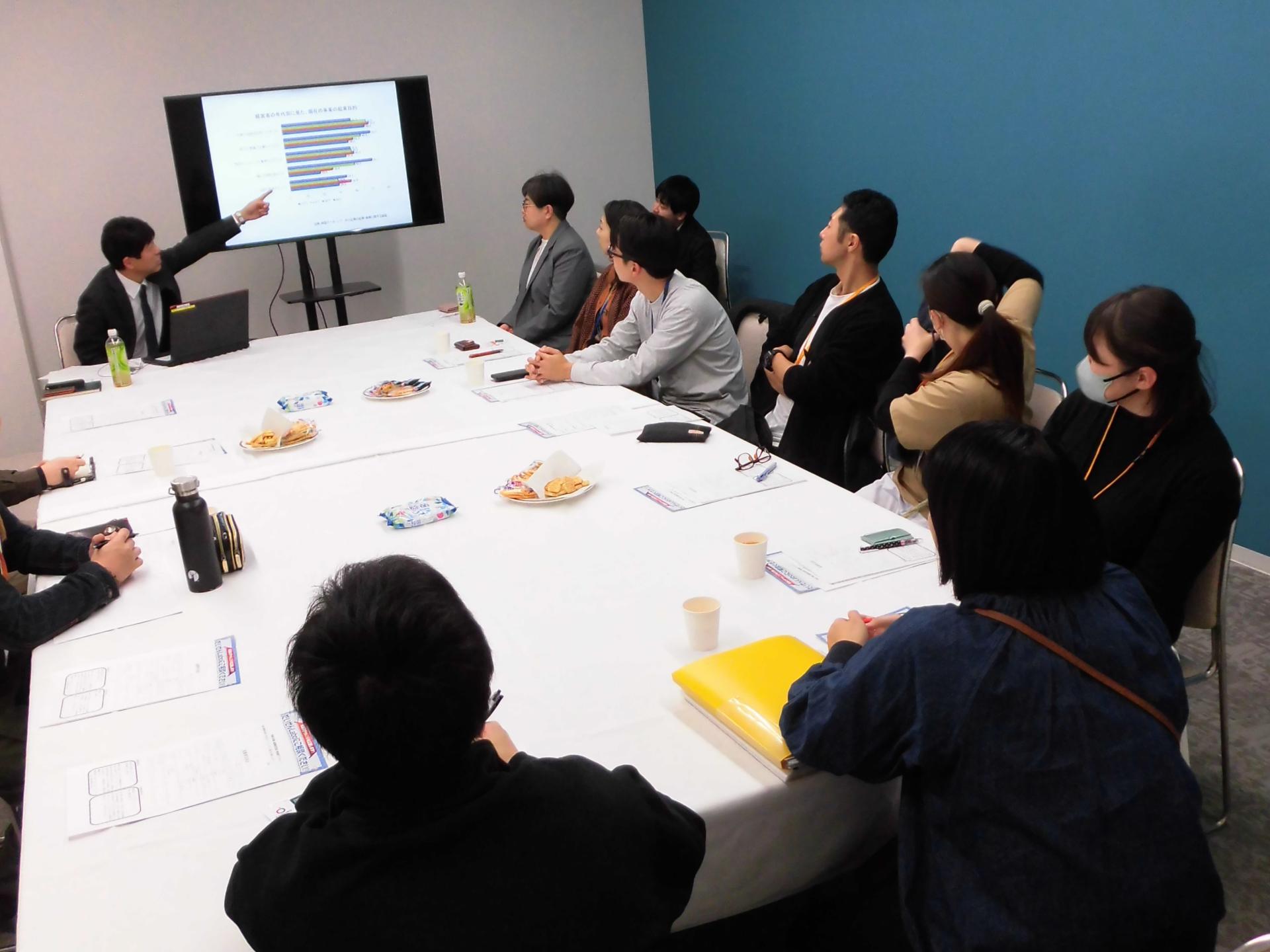 会議室で数名がモニターをみながら説明を聞いている