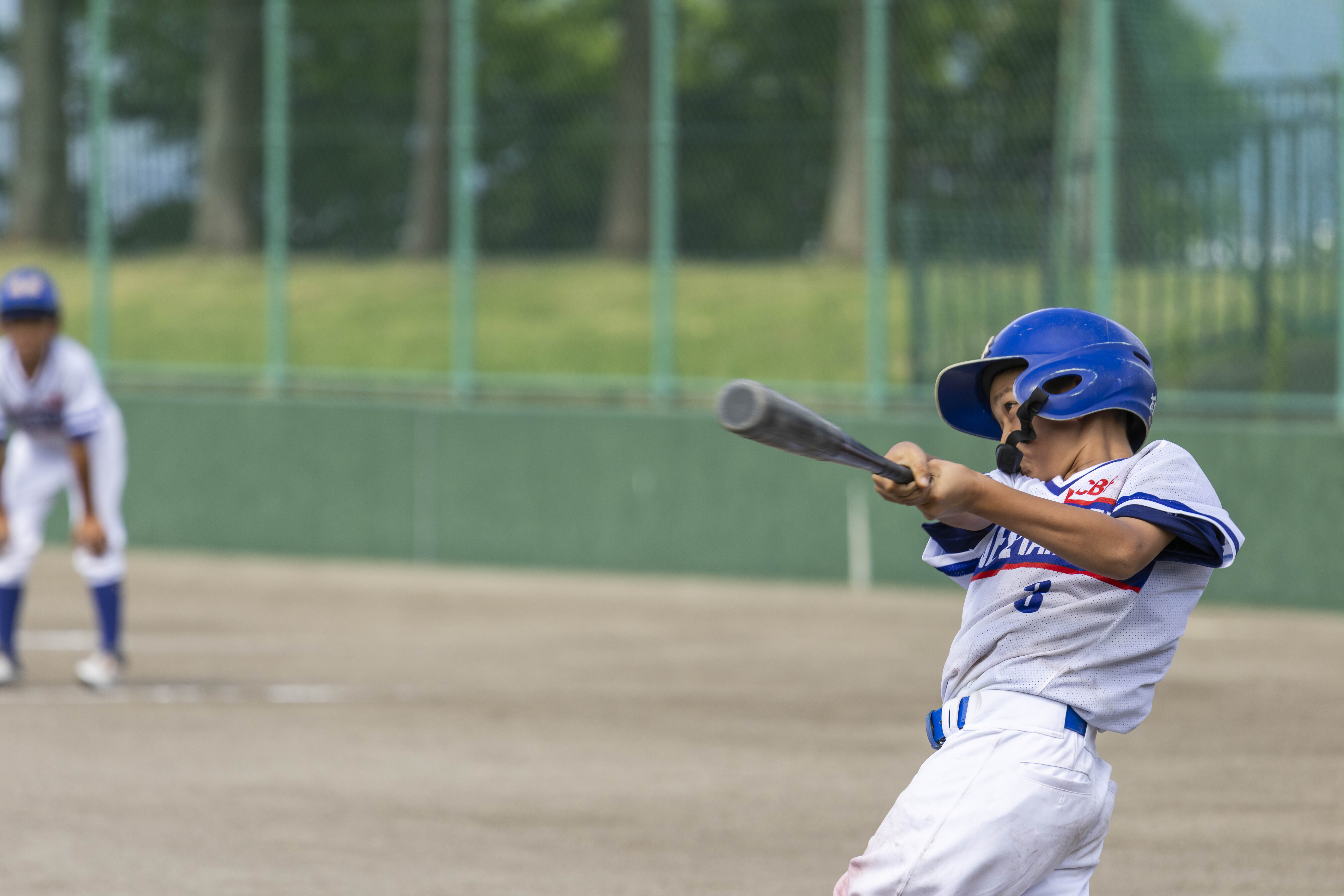 右バッターの少年が力強いスイングをしている様子