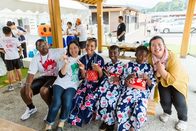 浴衣を着た外国の少女3人とスタッフの集合写真
