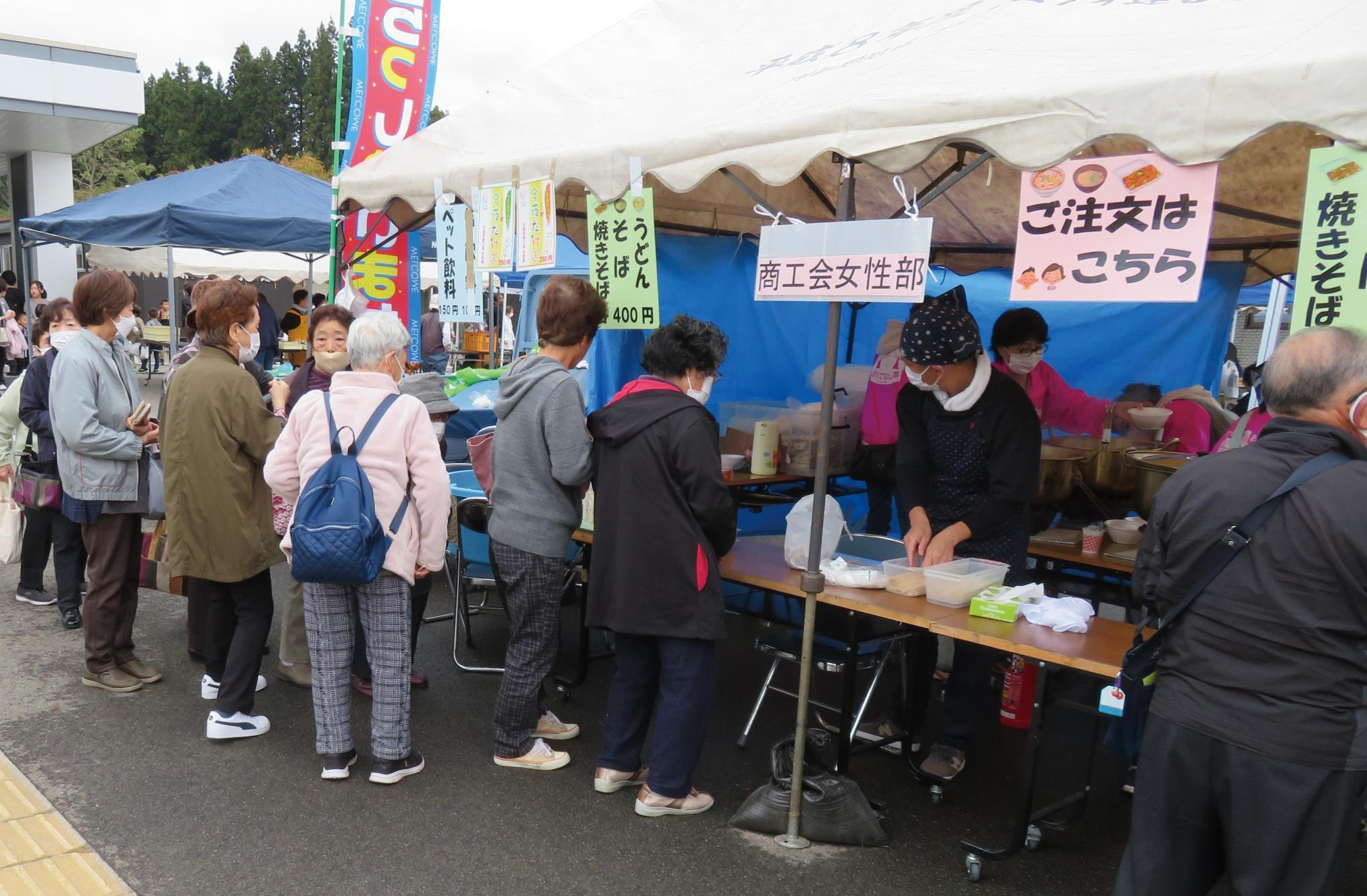 屋外での出店の様子、テント屋台で品定めすれる人々