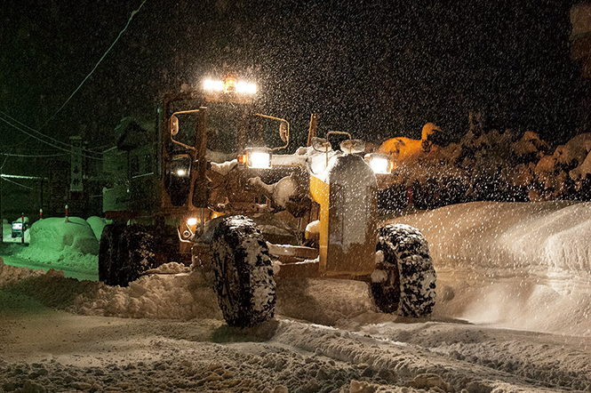 夜間の雪の中、稼働中の除雪車両