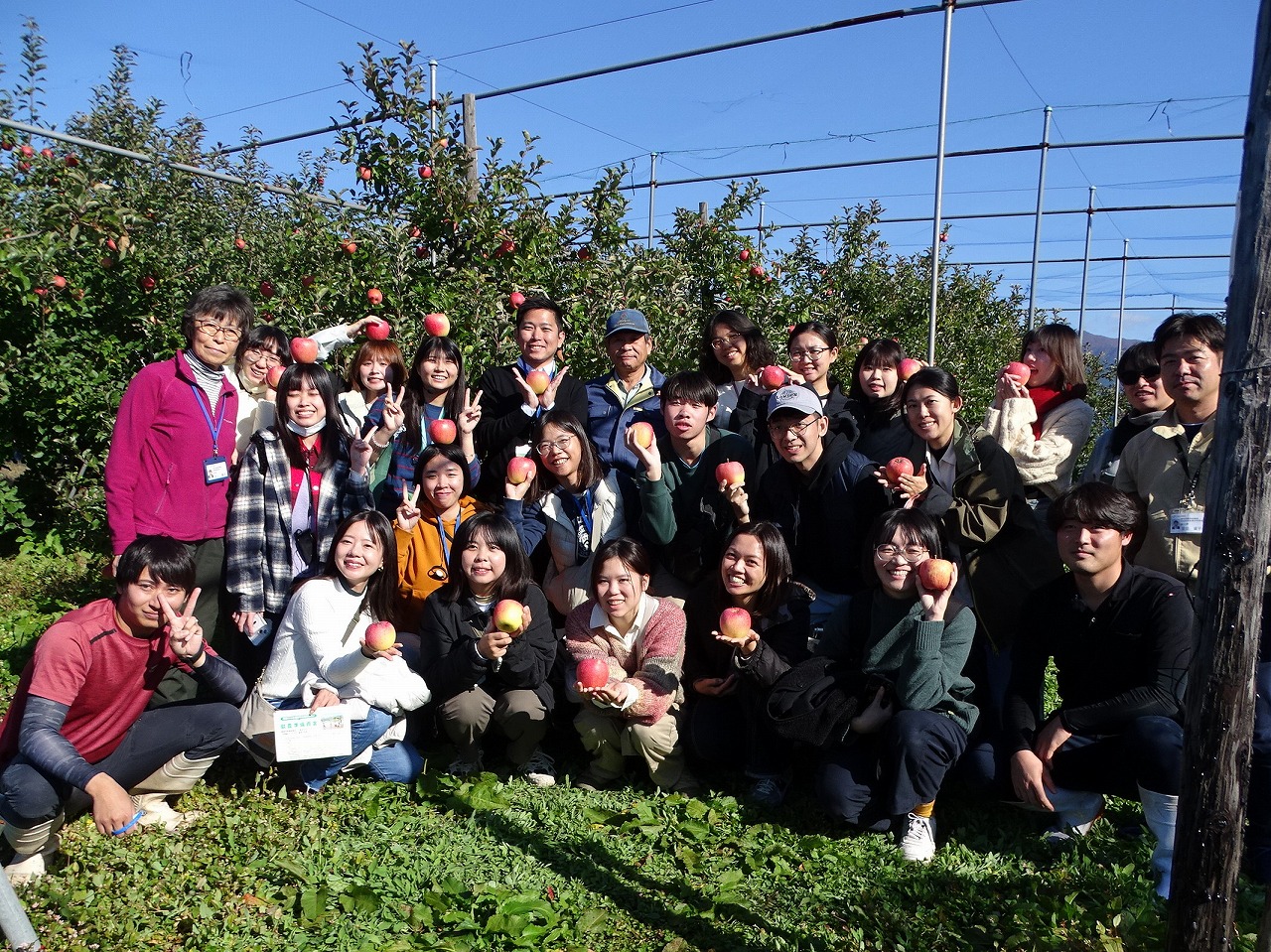 リンゴを手に記念撮影をする研修生と台湾の学生たち