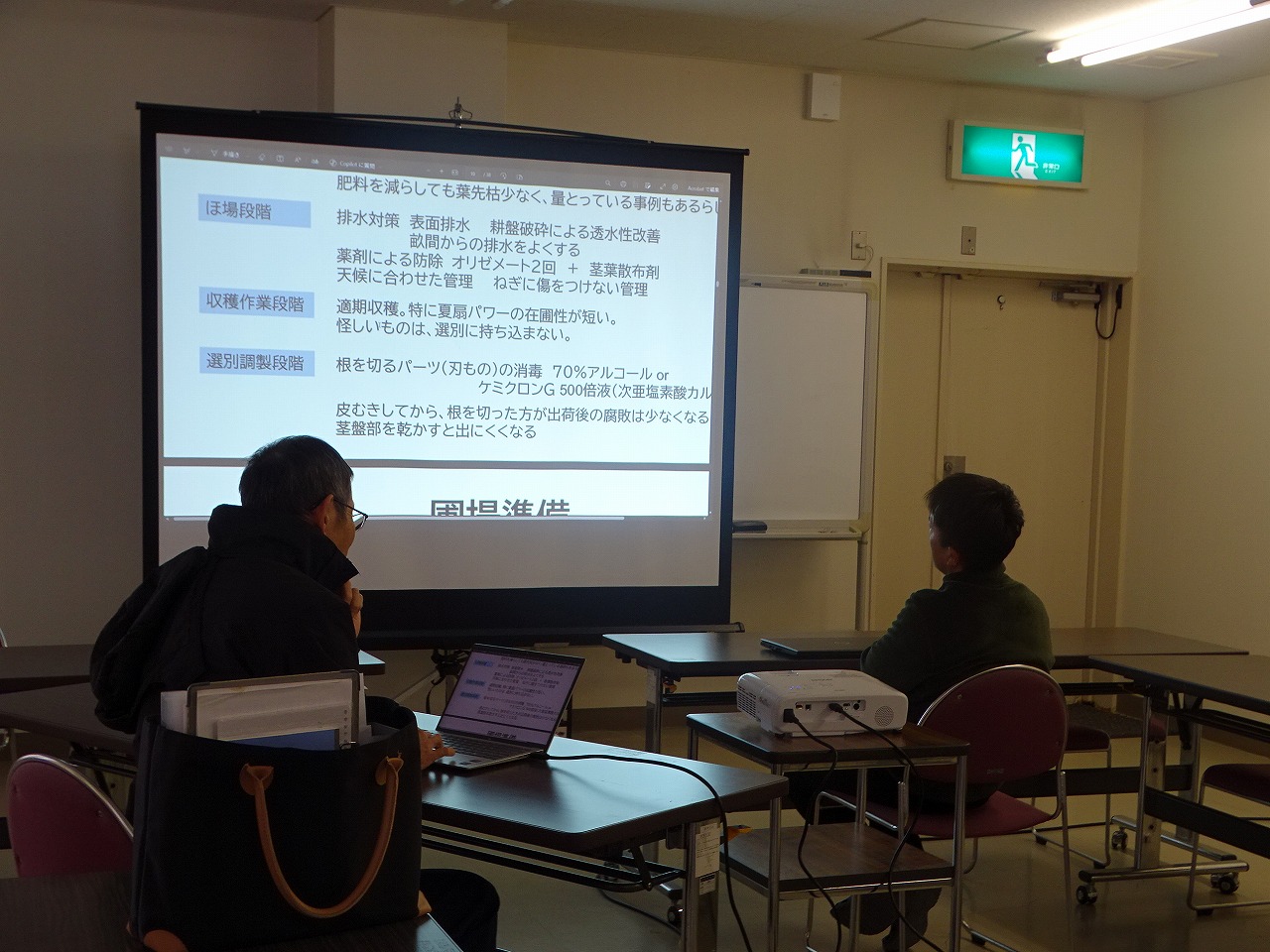 スクリーンに映し出されたパワーポイントの資料を読む研修生