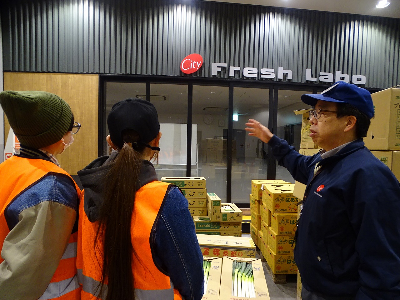 出荷された青果をPRするブースを視察する研修生