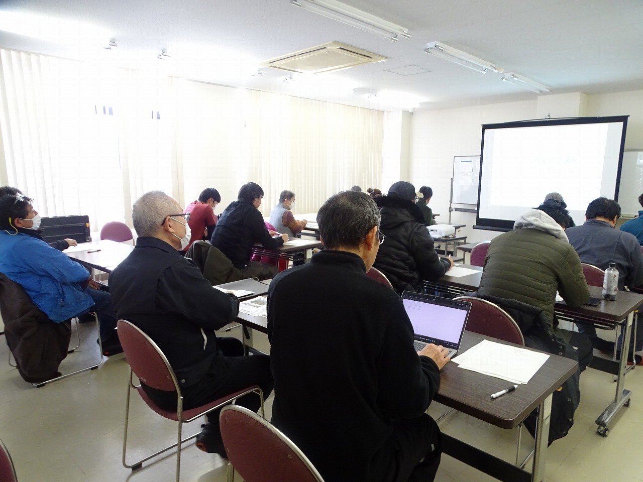 基礎講座の様子、研修室にスクリーンが設置されていて、約20人程度の参加者