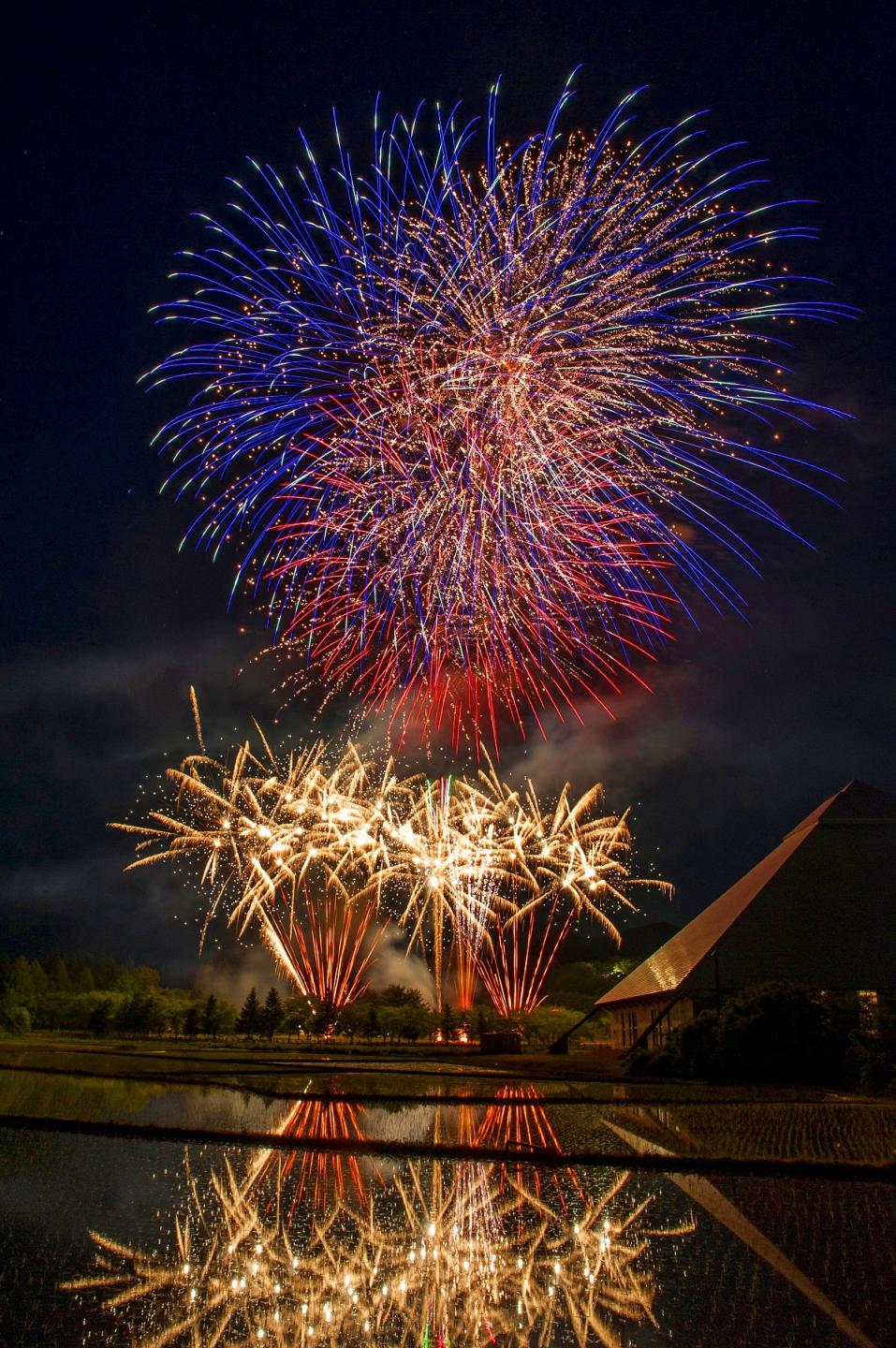 過去のイベントの写真（花火が打ち上がると同時に田んぼの水面に鏡のように写る花火）