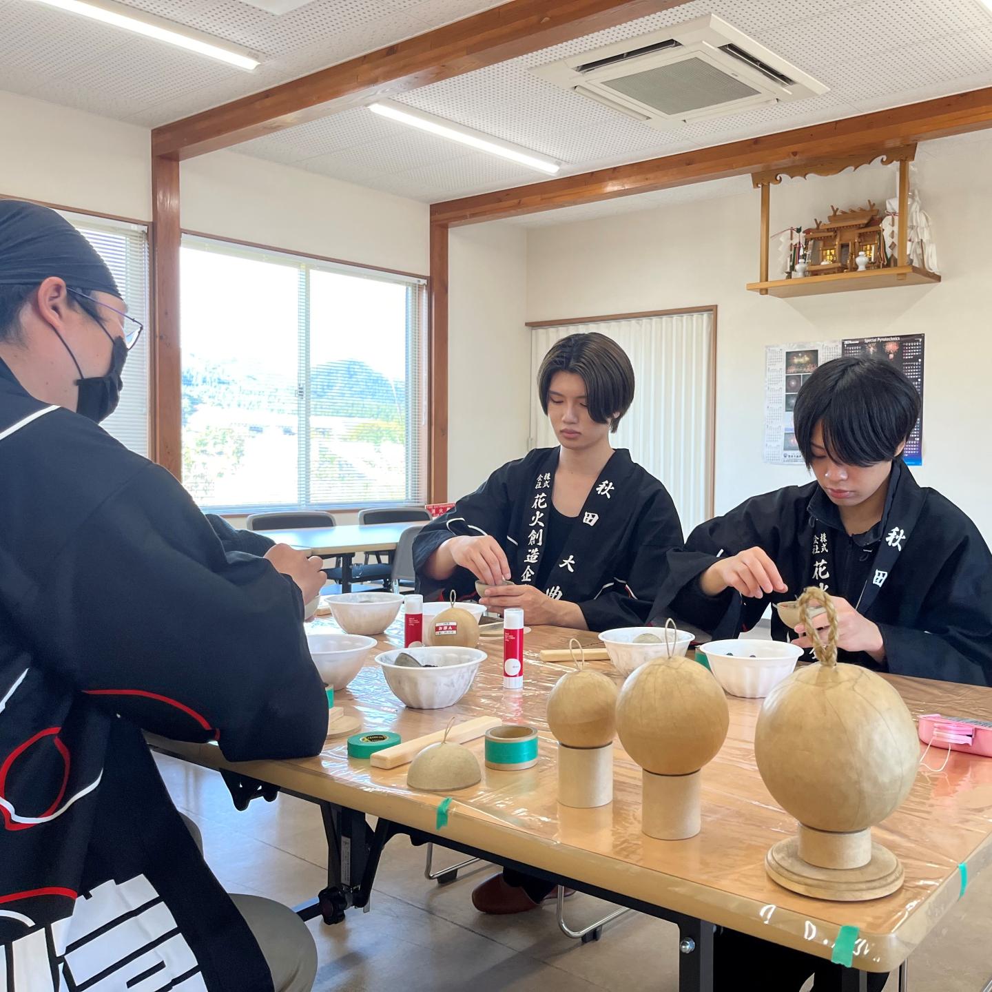 花火玉作り体験をする様子、法被を着た男性2人