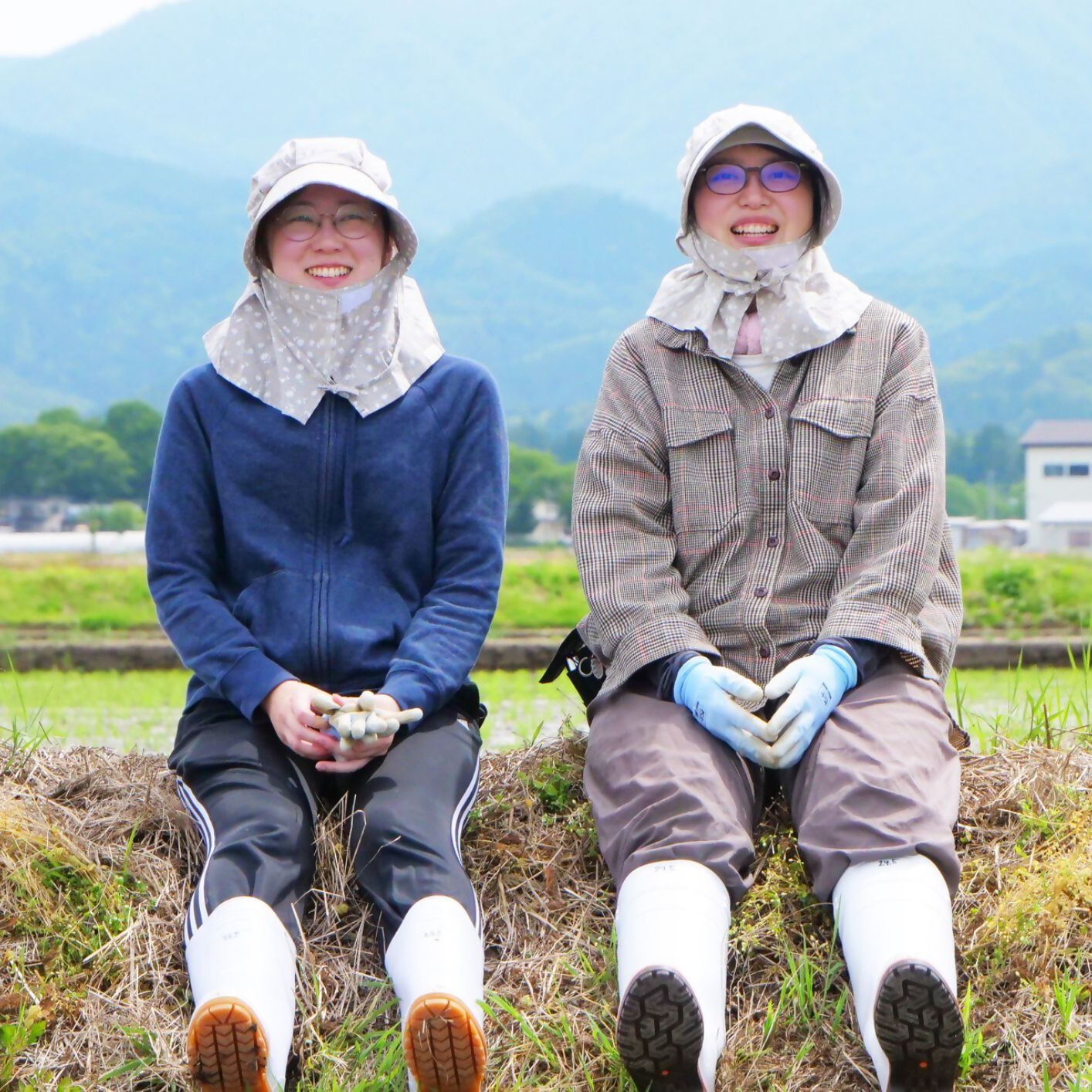 過去の体験ツアーの一コマ、農作業体験の合間の休憩、作業服と長靴をはいた女性2人