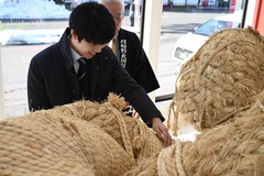 画像:藤井聡太竜王が大きな綱を両手で触り、笑顔を浮かべている様子