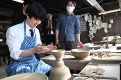 画像:藤井聡太竜王が陶芸体験の茶碗の前で笑顔を見せている様子