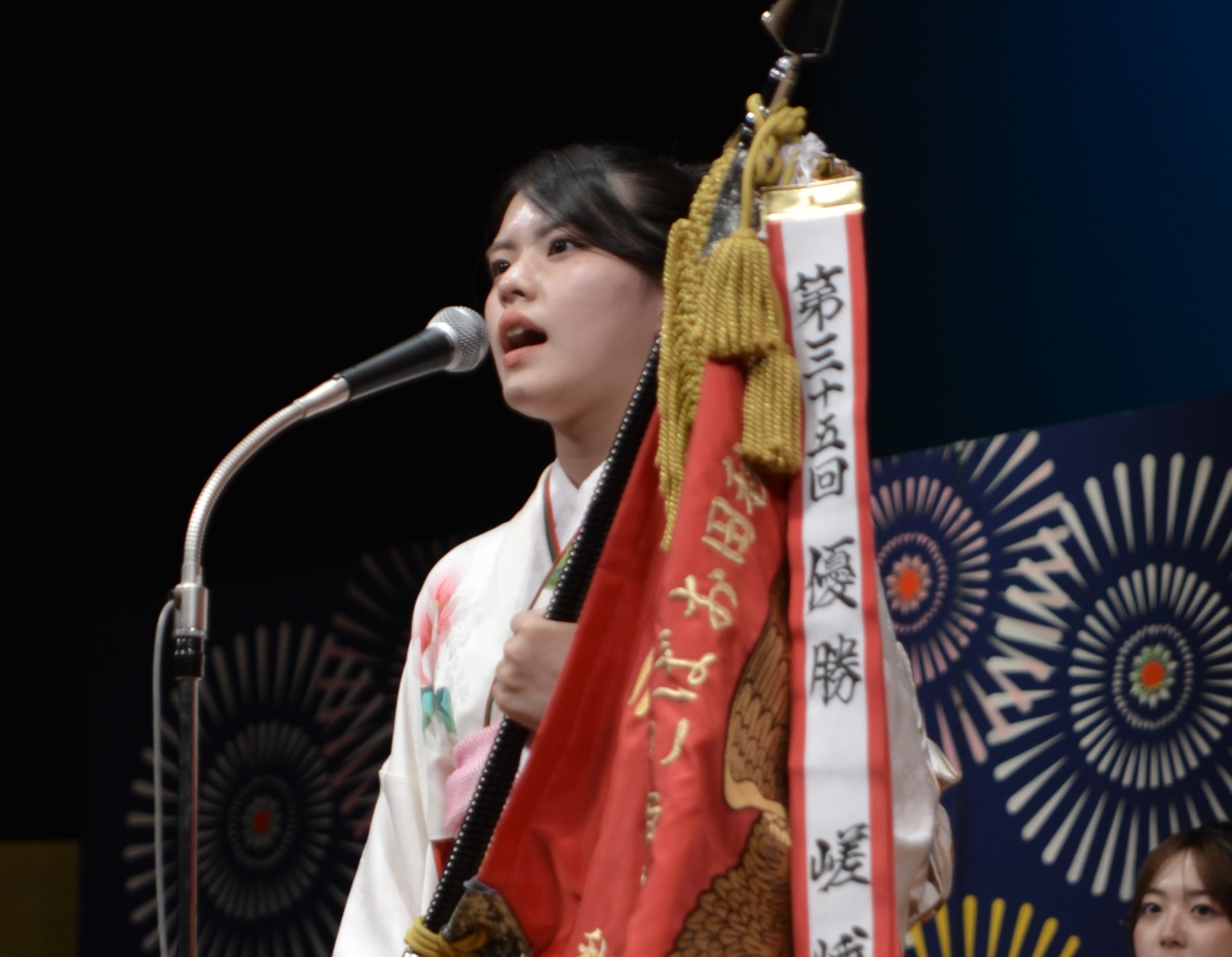 大会優勝旗を持って唄う嵯峨さん