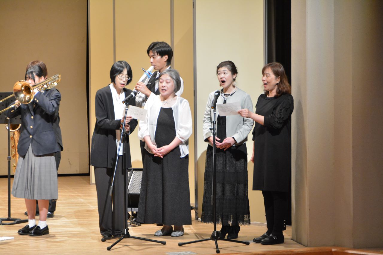 数名の男女が楽器演奏と合唱