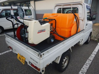 軽トラの荷台に積載された、防除機と希釈した薬剤を入れるタンク