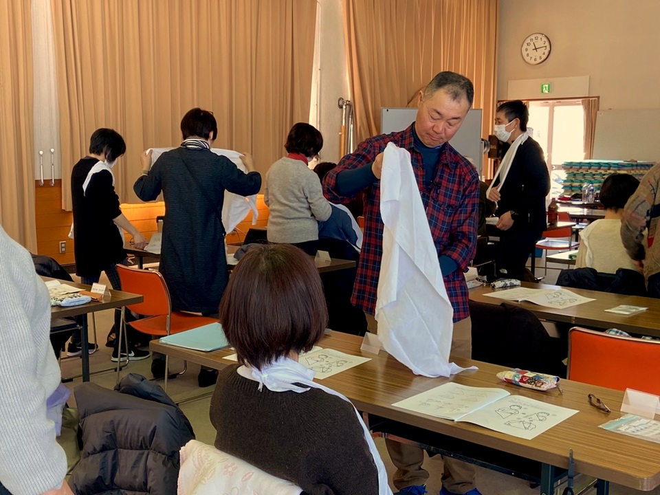 座学の様子、講師から三角巾の使用方法を学ぶ受講生