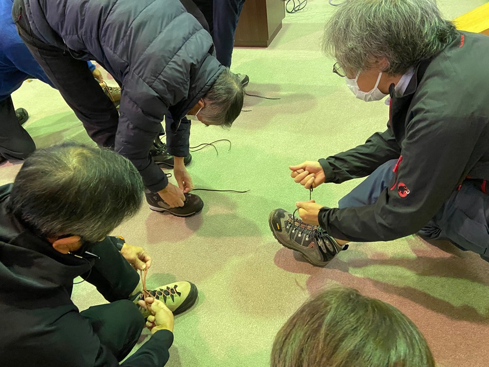 座学の様子、登山靴の紐の結び方を教わる受講生