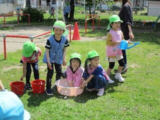 (芝生の上で幼児たちが笑顔で遊んでいる)すこやか子育て支援事業のイメージ写真