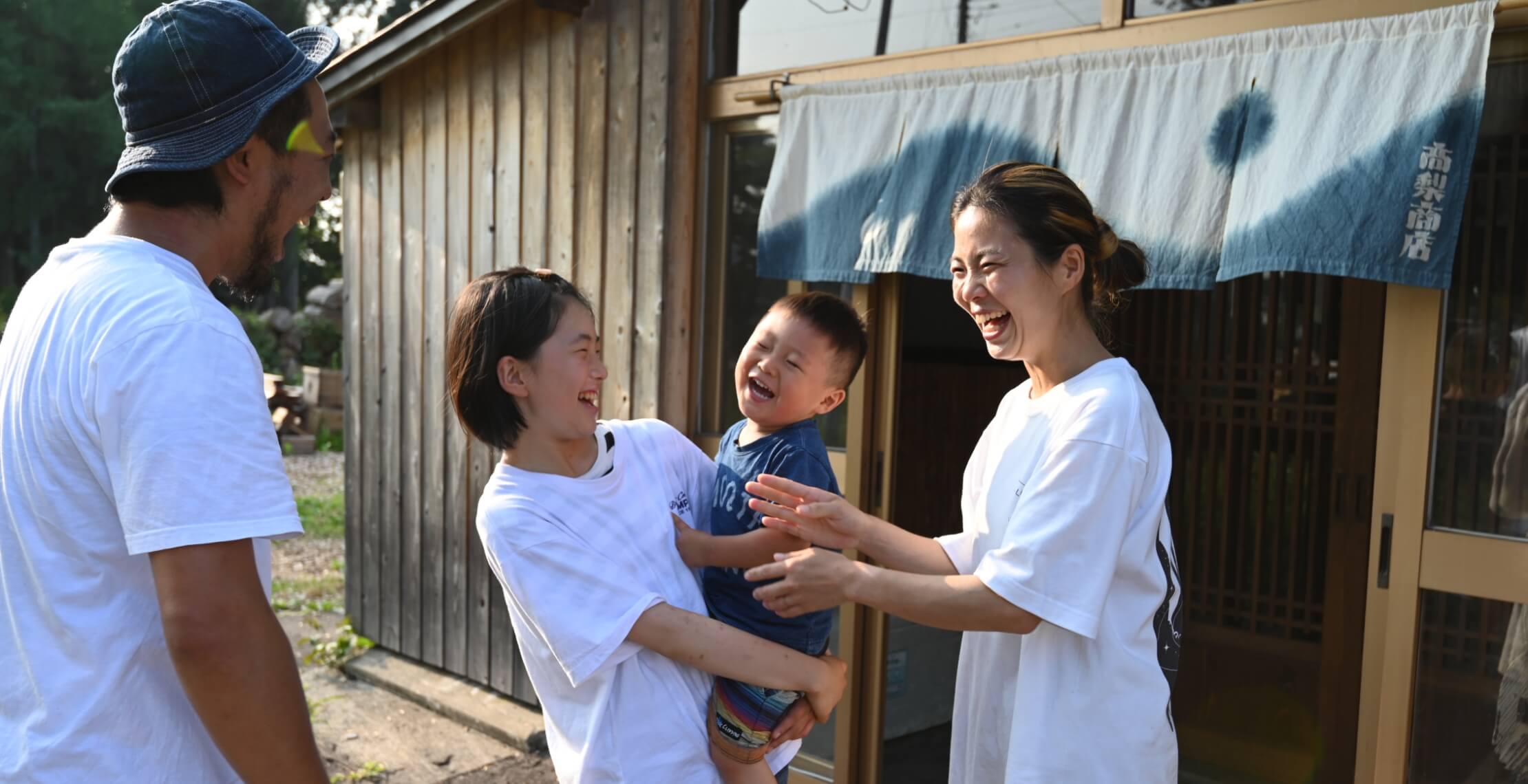 お店の前で笑顔で松本さん一家4人で写している写真