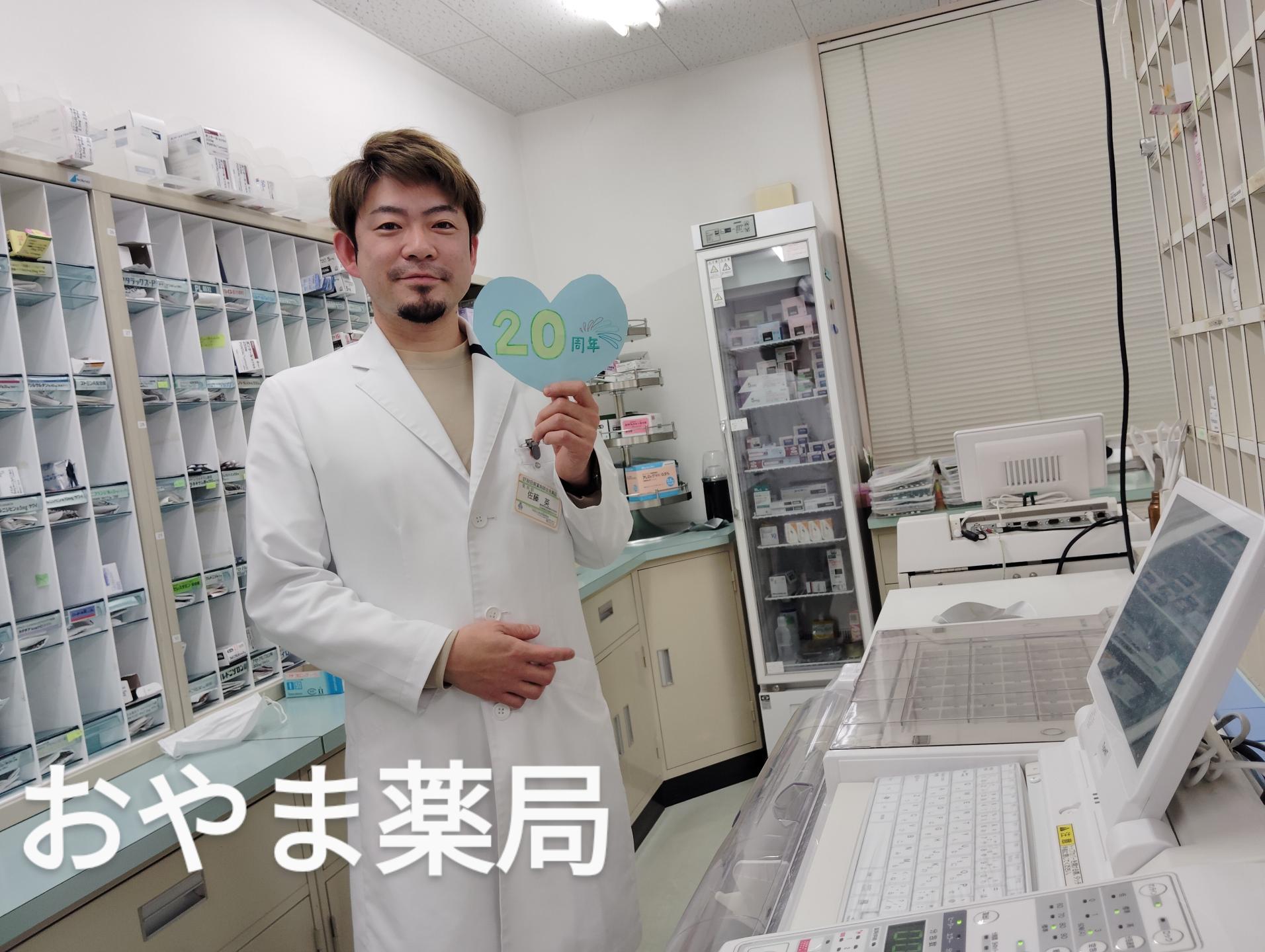 白衣をきてポーズをとる佐藤英さん