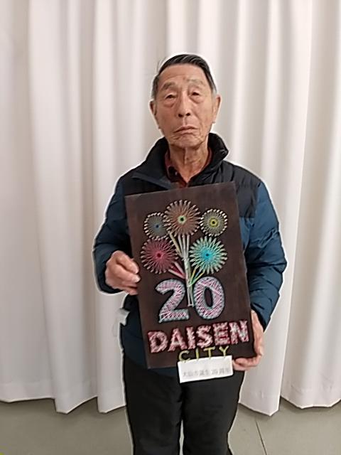 ストリングアートで作ったロゴマークを持つ男性