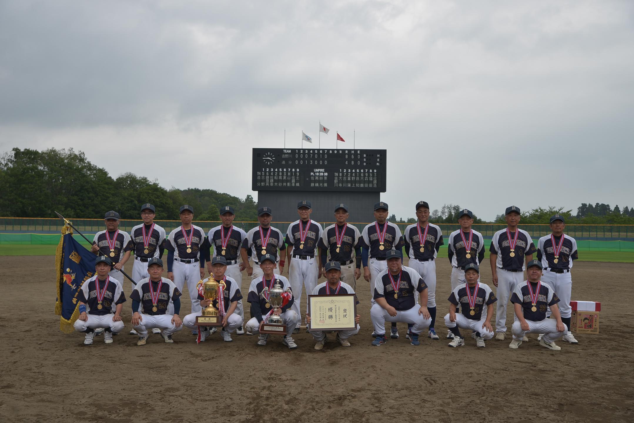 決勝戦のスコアが掲示されたスコアボードの前での集合写真