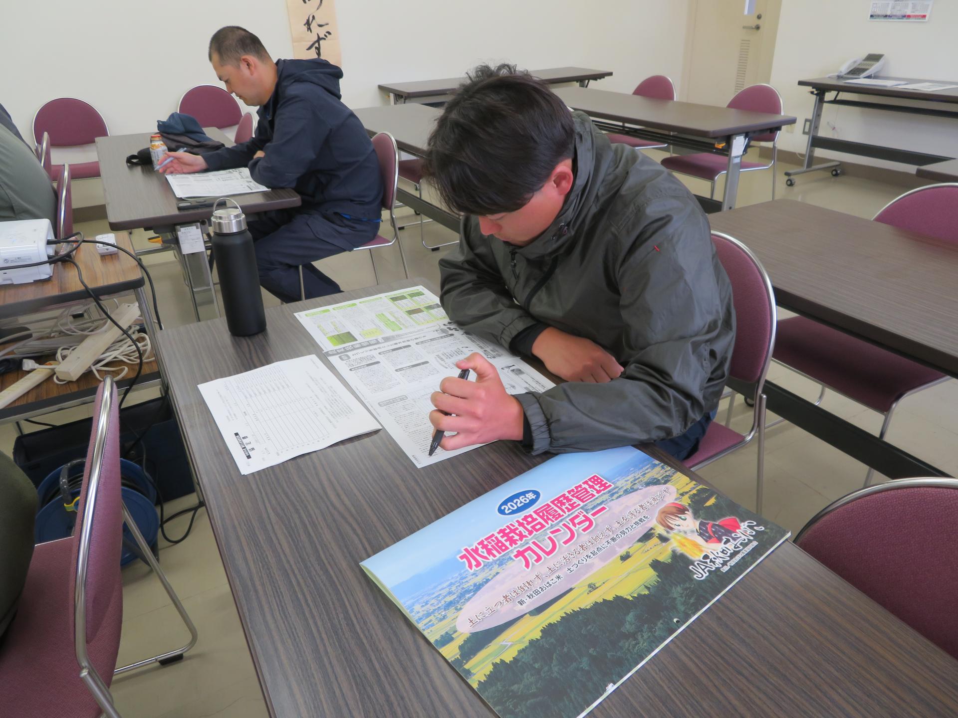 JA秋田おばこの広報誌やカレンダーを机に広げ、真剣に講義を聞く研修生たち
