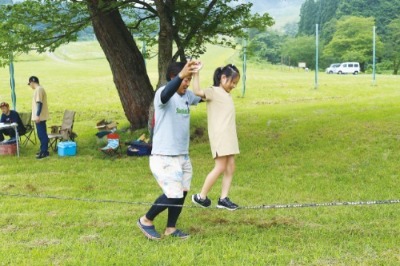 介助されながらロープの上をバランスを取って歩く少女