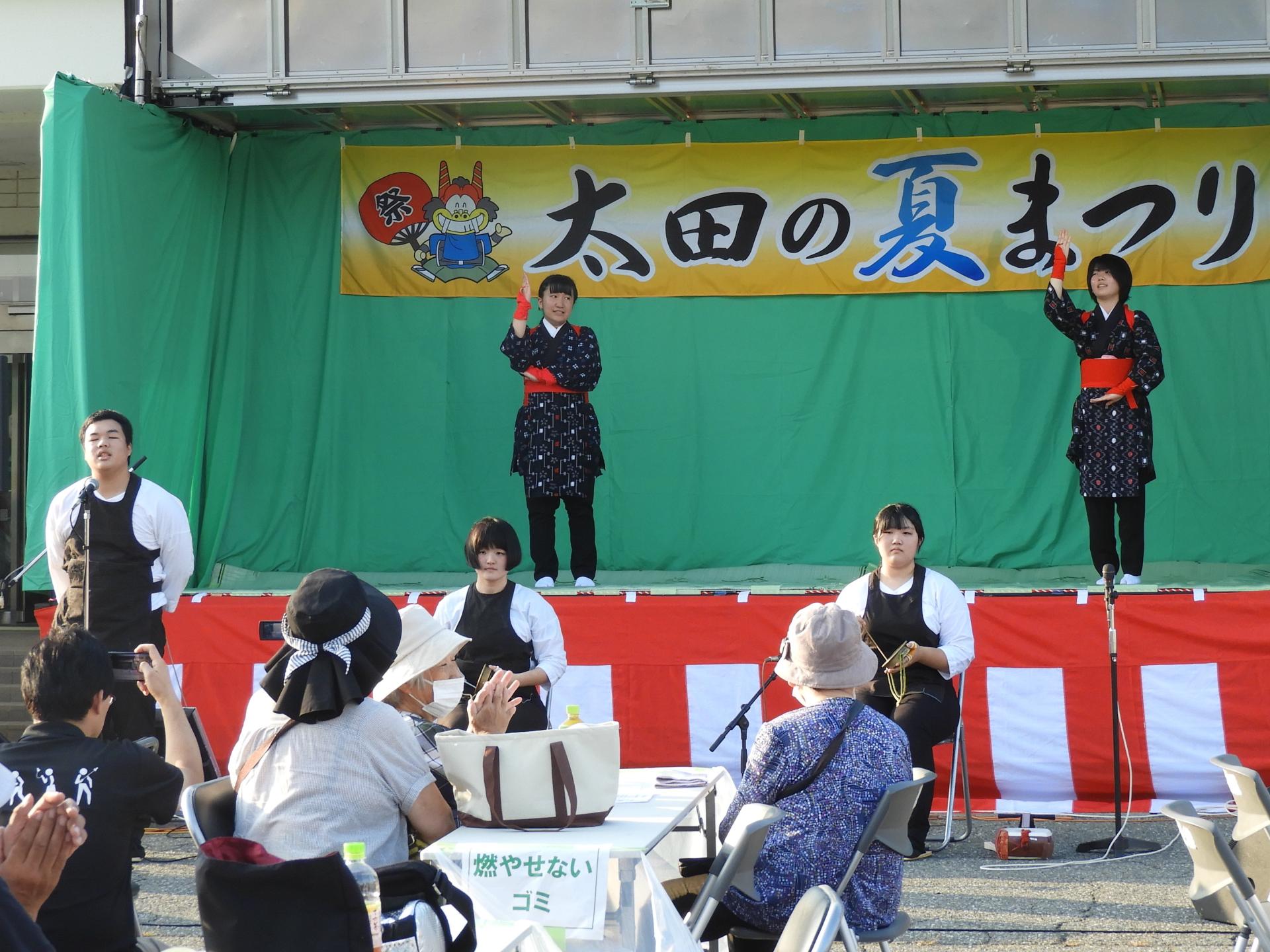 ステージ上と前で踊りと演奏をする高校生