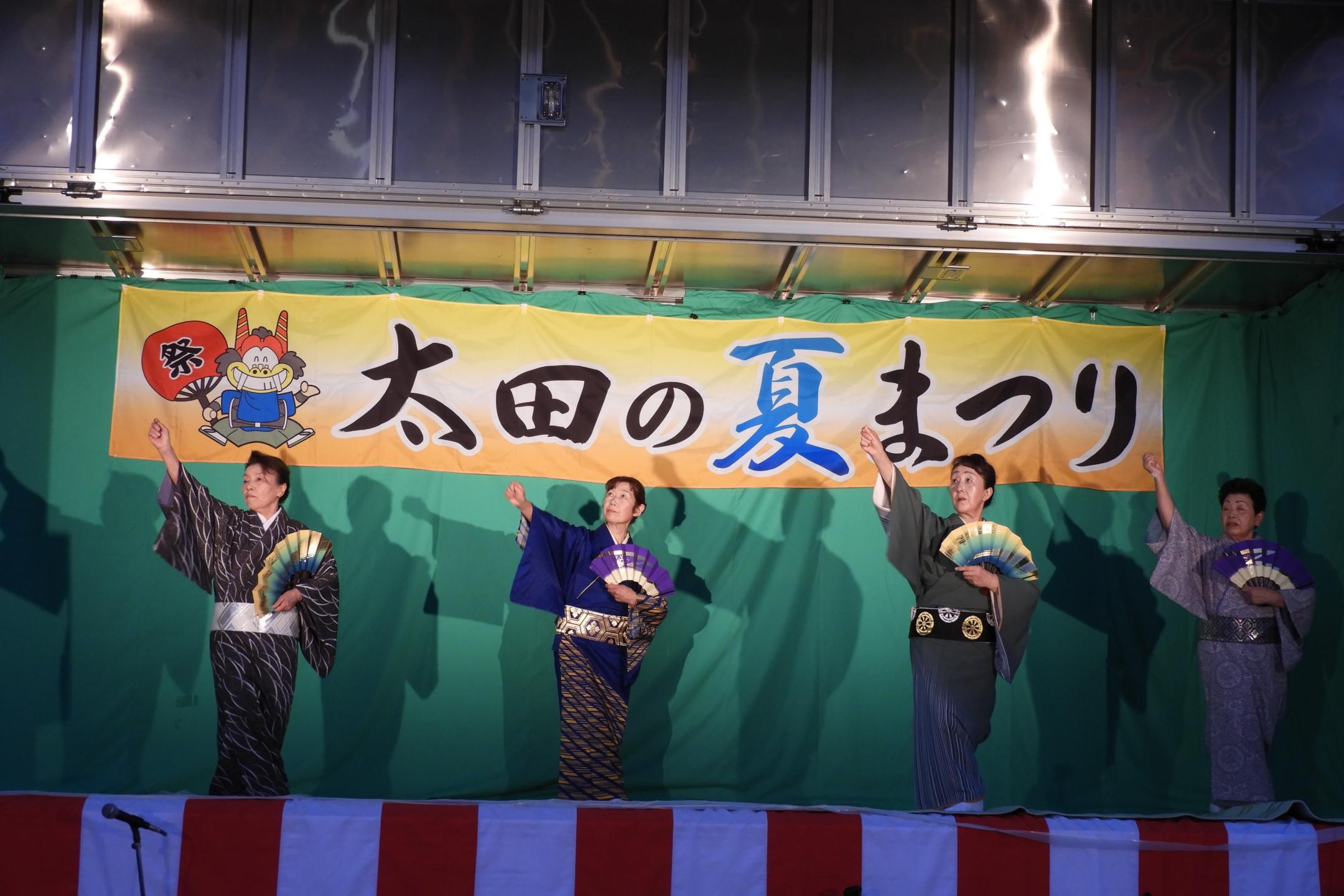 舞台上で着物を着た4人の女性が踊っている