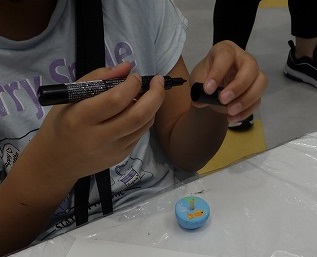 ワークショップの様子、参加者が絵付けした木製のコマ